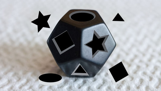 A black dodecahedron resembling a child's shapes puzzle toy. It is surrounded by the four cut-out pieces from its facing flat sides. The pieces are arranged in opposition to the missing ones on the dodecahedron.